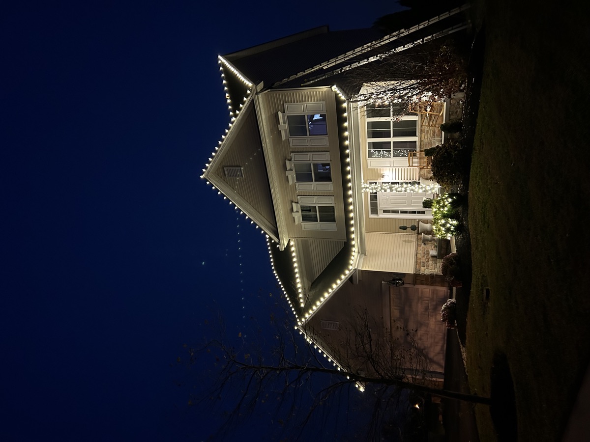 Warm white C9 bulbs outlining every peak and gable of a two-story house at dusk